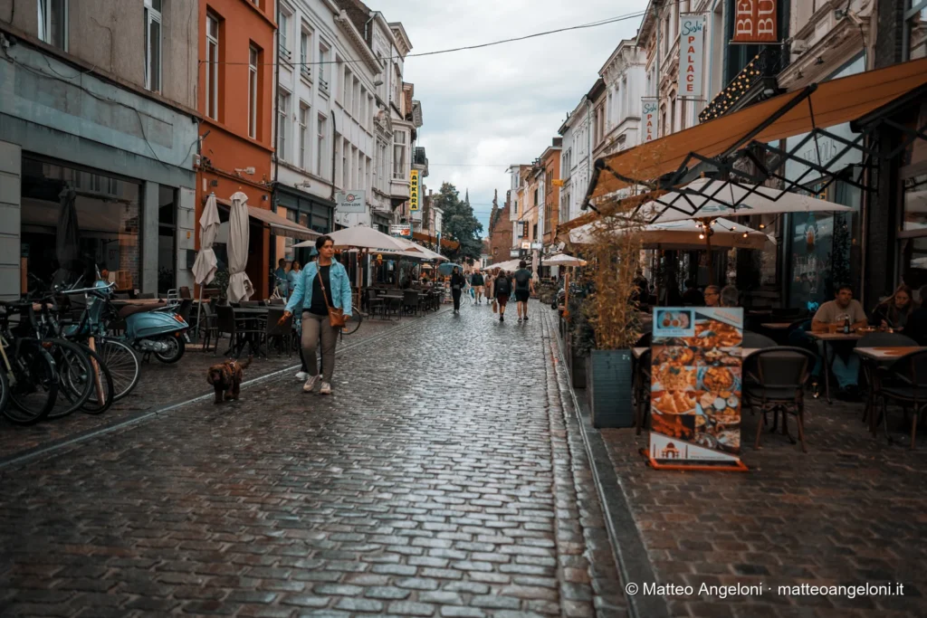 Via acciottolata con caffè e passanti nel centro di Gand