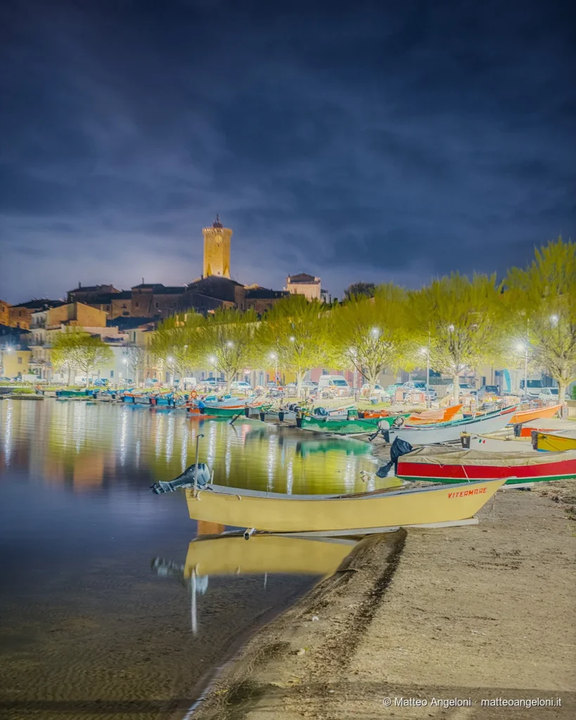 Barche sulla riva e torre illuminata sul Lago di Bolsena di notte