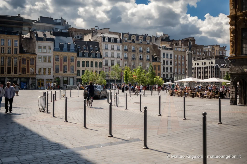 Grand Place di Lille con ciclisti, pedoni e caffè all'aperto