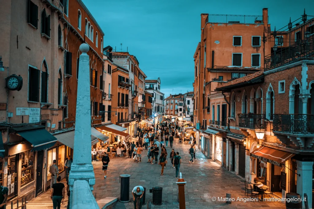 Calle affollata tra palazzi veneziani durante l'ora blu