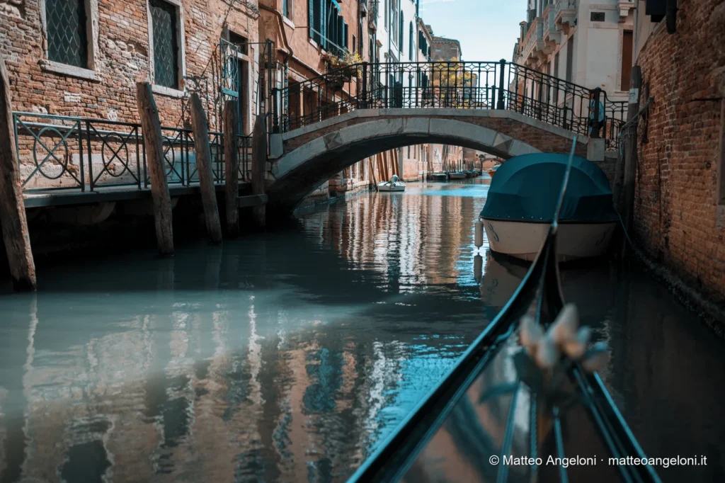 Vista da una gondola mentre passa sotto un ponte veneziano