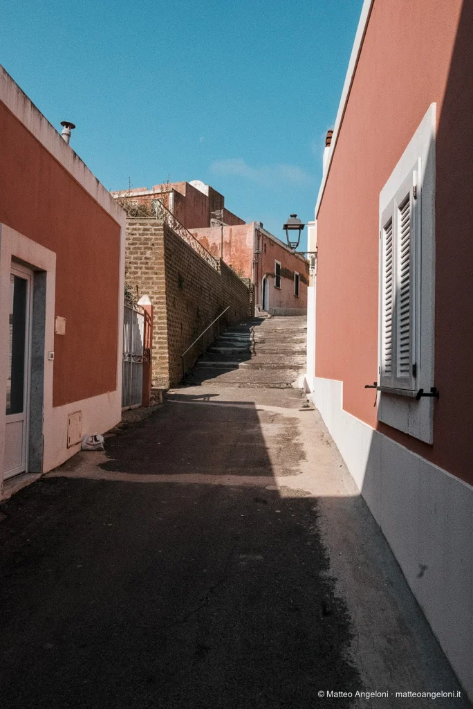Case rosse e scala in un vicolo assolato di Ventotene